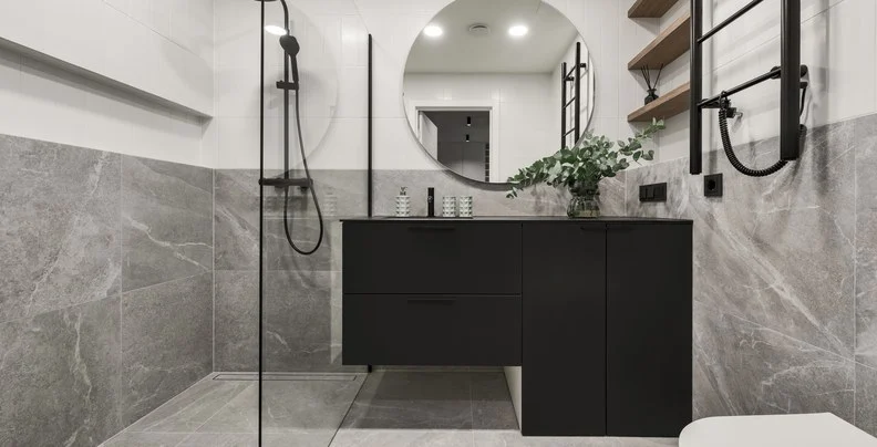 Badezimmer mit bodengleicher Dusche, Rundspiegel und Feinsteinzeug